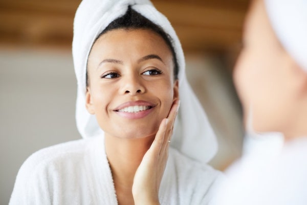 woman looking at skin in mirror