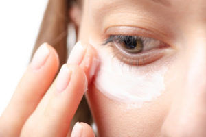Closeup of woman applying eye cream