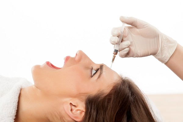 Woman looking fearful as she receives a facial injection