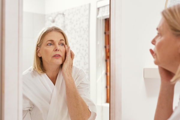 Woman concerned about dry facial skin in mirror reflection